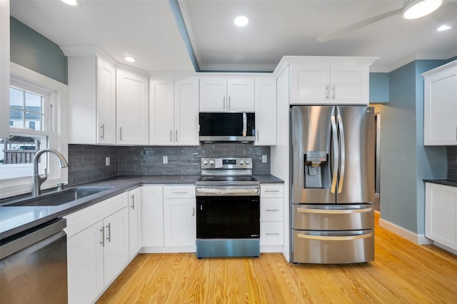 kitchen featuring dark countertops, light wood-type flooring, stainless steel appliances, and a sink