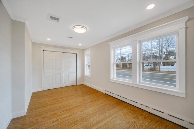 unfurnished bedroom featuring a closet, visible vents, light wood-style flooring, baseboard heating, and baseboards