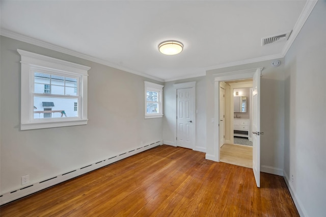 unfurnished bedroom with baseboards, visible vents, wood finished floors, baseboard heating, and crown molding