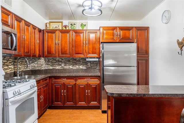 kitchen with stainless steel appliances, sink, backsplash, and light hardwood / wood-style flooring