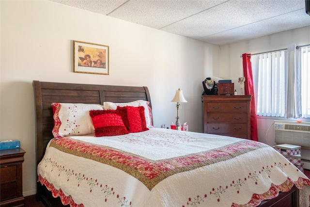 bedroom featuring a paneled ceiling and an AC wall unit