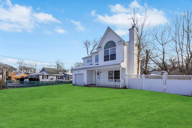 rear view of property with a garage, covered porch, and a lawn