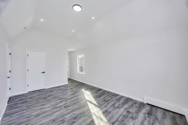 spare room featuring high vaulted ceiling, hardwood / wood-style floors, and a baseboard heating unit