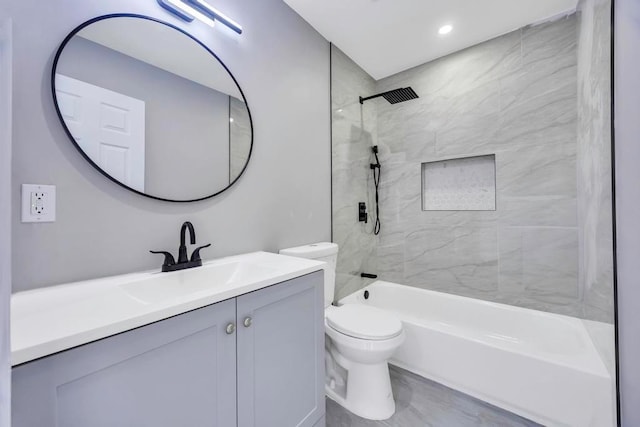 full bathroom featuring vanity, tiled shower / bath combo, and toilet