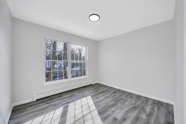 unfurnished room featuring wood-type flooring and baseboard heating