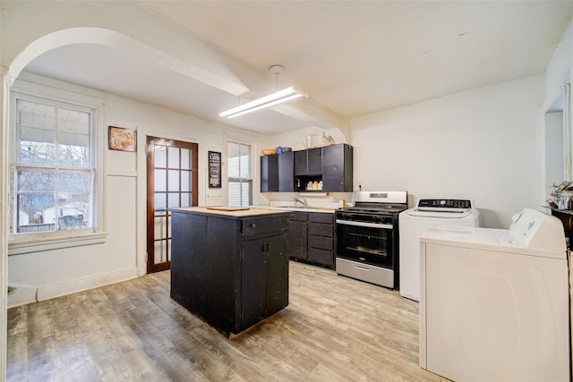 kitchen featuring sink, light hardwood / wood-style flooring, stainless steel range with gas stovetop, washing machine and clothes dryer, and a kitchen island