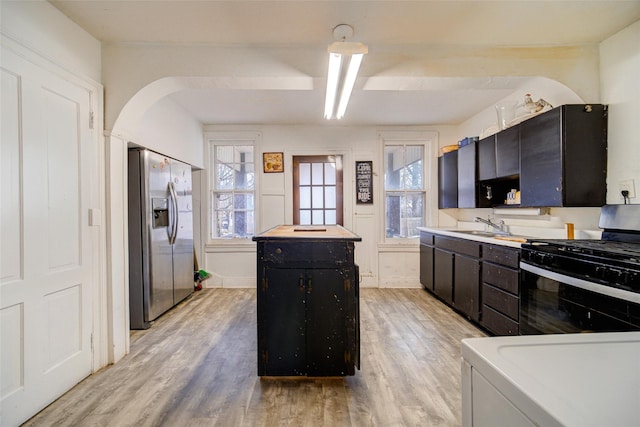 kitchen featuring sink, a center island, gas stove, stainless steel refrigerator with ice dispenser, and light hardwood / wood-style flooring