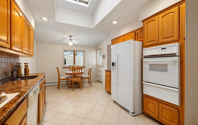 kitchen featuring sink, dishwashing machine, white fridge with ice dispenser, ceiling fan, and backsplash