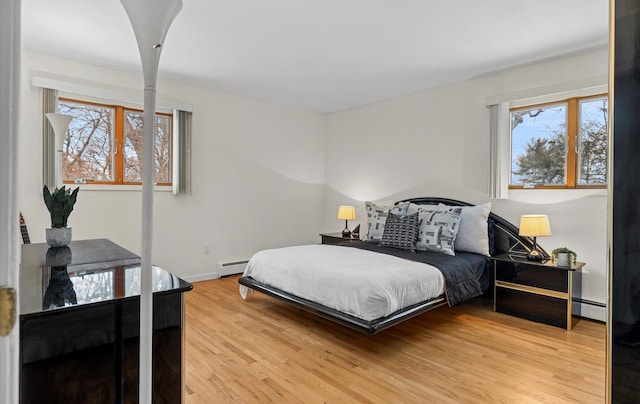 bedroom with a baseboard heating unit and light hardwood / wood-style flooring