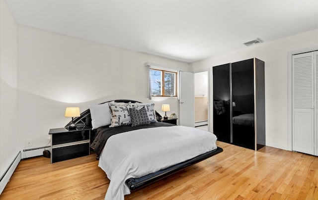 bedroom with a baseboard radiator, light hardwood / wood-style floors, and a closet