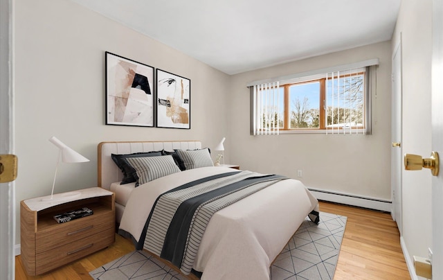 bedroom with light wood-type flooring and a baseboard heating unit