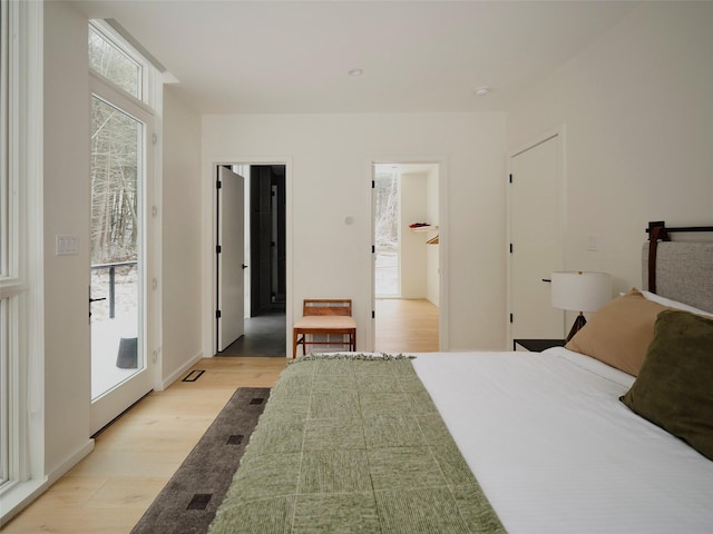 bedroom with ensuite bath, access to exterior, and light hardwood / wood-style flooring