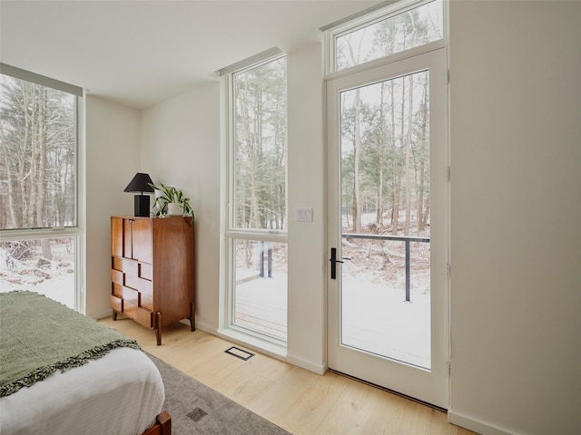 bedroom with multiple windows, access to outside, and light hardwood / wood-style floors