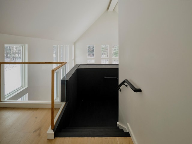 stairs with hardwood / wood-style floors and vaulted ceiling with beams