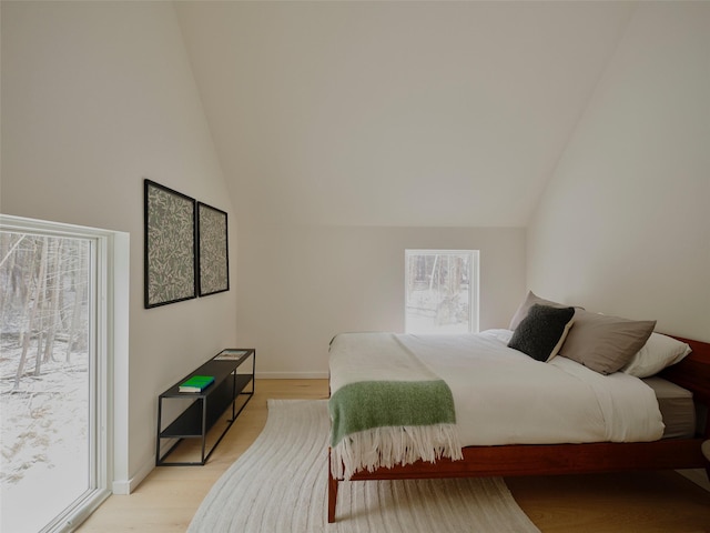 bedroom featuring vaulted ceiling, access to exterior, and light hardwood / wood-style flooring