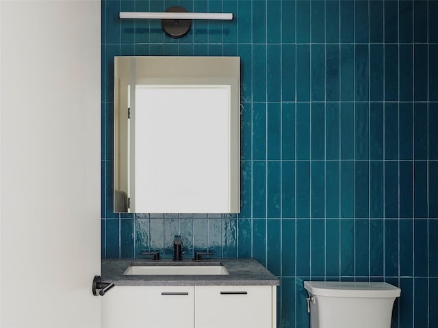 bathroom featuring vanity, tile walls, and toilet