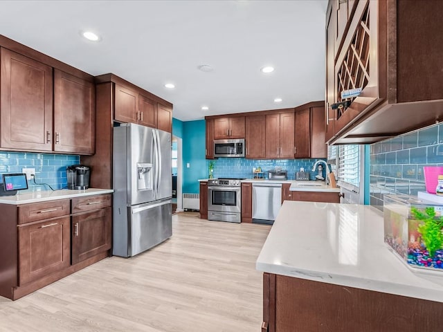 kitchen featuring sink, decorative backsplash, light hardwood / wood-style flooring, and appliances with stainless steel finishes