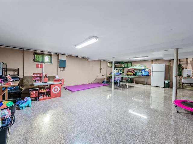 basement featuring white refrigerator and electric panel