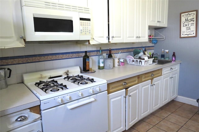 kitchen featuring sink, white cabinetry, tasteful backsplash, light tile patterned floors, and white appliances