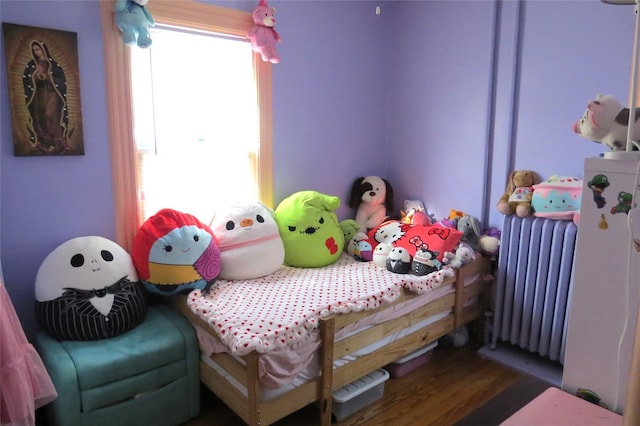 bedroom with dark hardwood / wood-style flooring and radiator heating unit