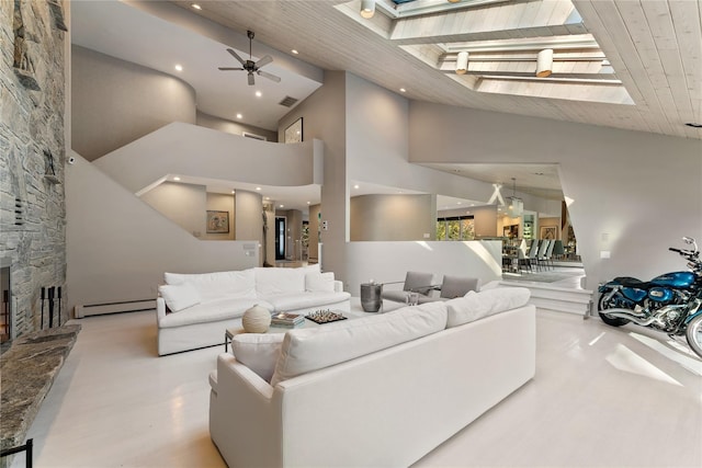 living room featuring a stone fireplace, a towering ceiling, a skylight, a baseboard heating unit, and wood ceiling