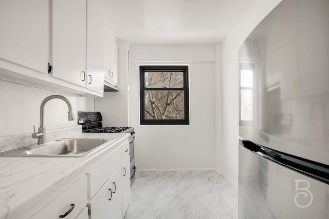 kitchen featuring stainless steel fridge, sink, range with gas cooktop, and white cabinets