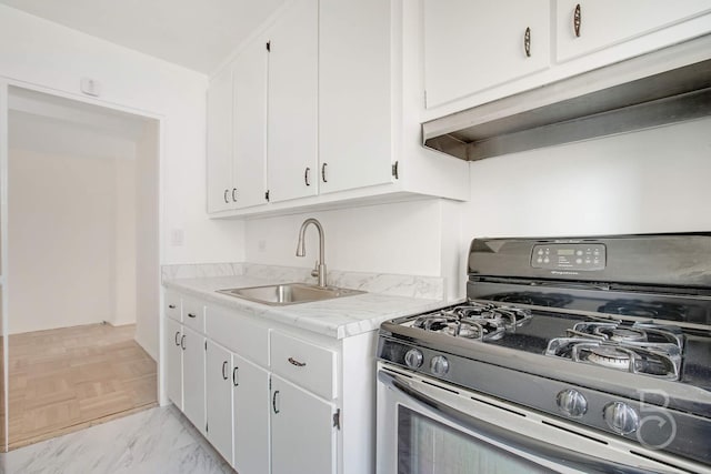 kitchen featuring sink, gas range, and white cabinets