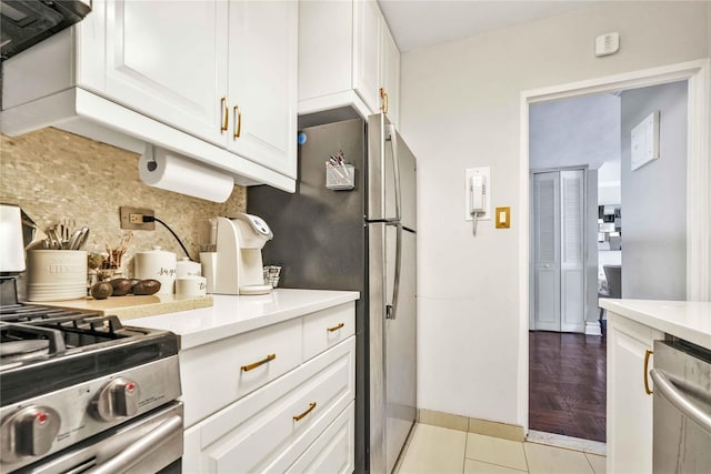 kitchen with light tile patterned floors, white cabinetry, stainless steel appliances, and backsplash