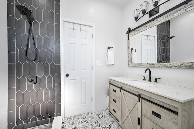 bathroom with tiled shower, vanity, and tile patterned flooring