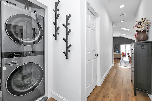 laundry room featuring stacked washer and clothes dryer and light wood-type flooring