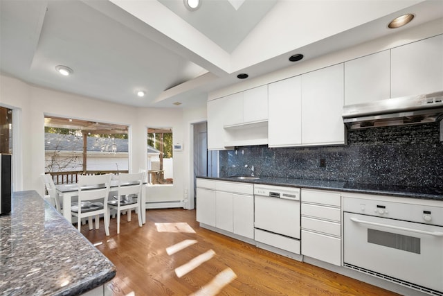 kitchen with white cabinetry, white appliances, light hardwood / wood-style floors, decorative backsplash, and a baseboard heating unit