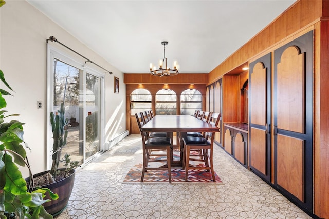 dining area featuring a baseboard radiator, wooden walls, and a chandelier