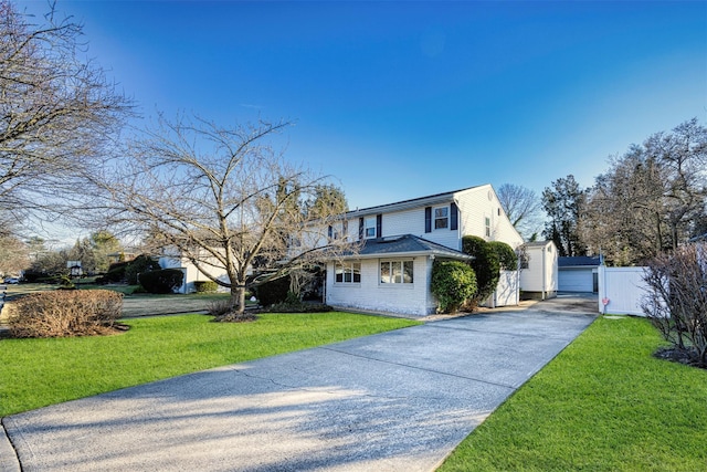 front facade featuring a garage, an outbuilding, and a front lawn