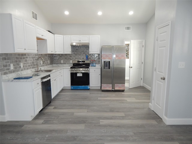 kitchen featuring sink, tasteful backsplash, light wood-type flooring, appliances with stainless steel finishes, and white cabinets