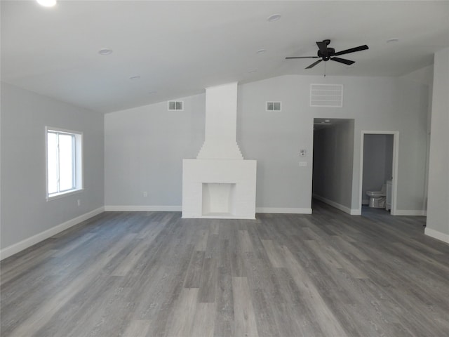 unfurnished living room with ceiling fan, lofted ceiling, hardwood / wood-style floors, and a fireplace