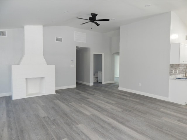 unfurnished living room with ceiling fan, sink, vaulted ceiling, and light wood-type flooring