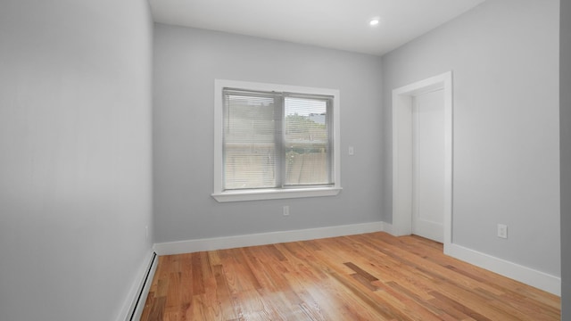 spare room featuring light wood-style floors, baseboards, and a baseboard heating unit