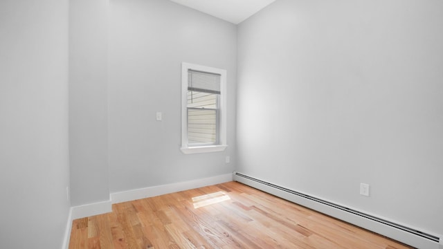 unfurnished room featuring baseboards, a baseboard heating unit, and wood finished floors