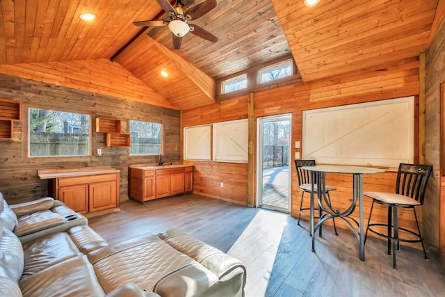 living room featuring high vaulted ceiling, wood walls, ceiling fan, wood ceiling, and light hardwood / wood-style flooring