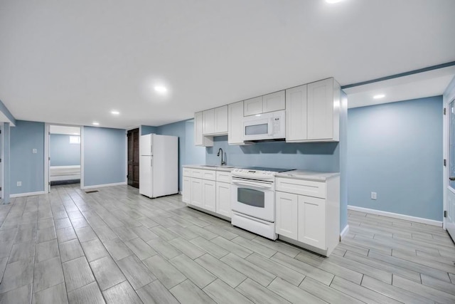 kitchen featuring white cabinetry, sink, and white appliances