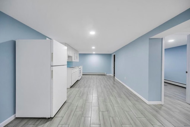 kitchen featuring white refrigerator, white cabinetry, and baseboard heating