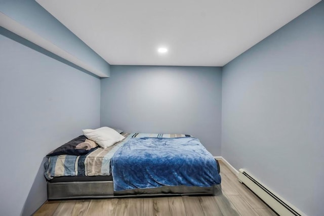 bedroom with wood-type flooring and a baseboard heating unit