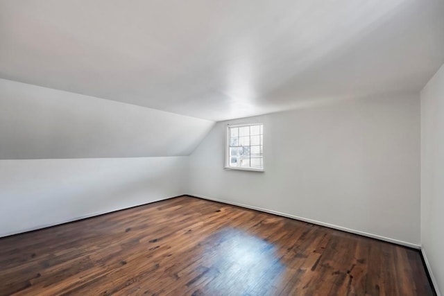 additional living space with dark wood-type flooring and vaulted ceiling