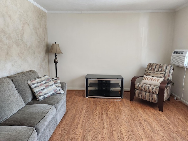 sitting room featuring ornamental molding, a wall unit AC, and light wood-type flooring