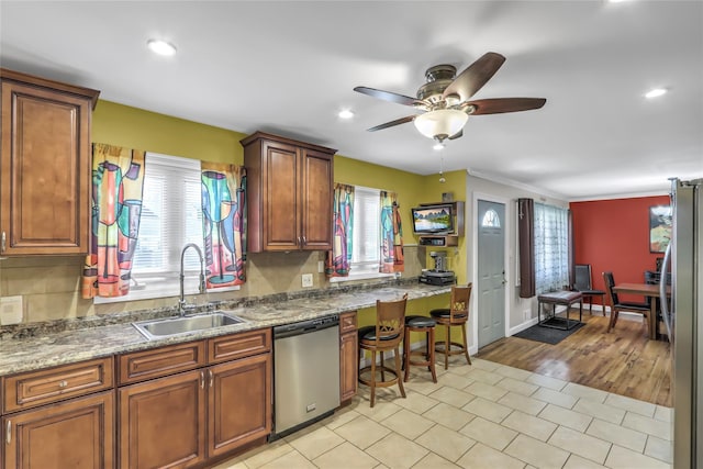 kitchen with light stone counters, appliances with stainless steel finishes, sink, and backsplash