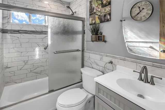 full bathroom featuring enclosed tub / shower combo, vanity, toilet, and tile walls