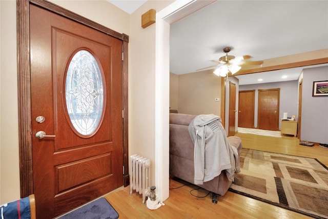 foyer with ceiling fan, radiator, and light wood-type flooring