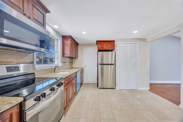 kitchen with stainless steel appliances, tasteful backsplash, sink, and light stone counters