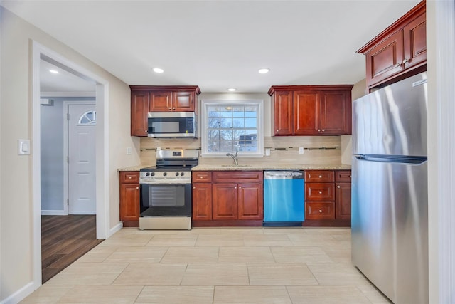 kitchen with stainless steel appliances, sink, light stone counters, and decorative backsplash