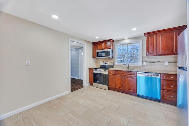 kitchen featuring light stone counters, stainless steel appliances, sink, and backsplash